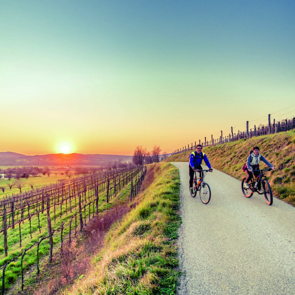 Biker couple riding moutain bike in the countryside at sunset